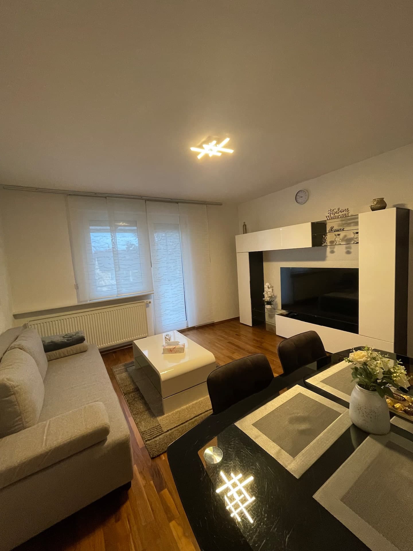 Wohnzimmer mit Esstisch, Sofa und moderner TV-Wand