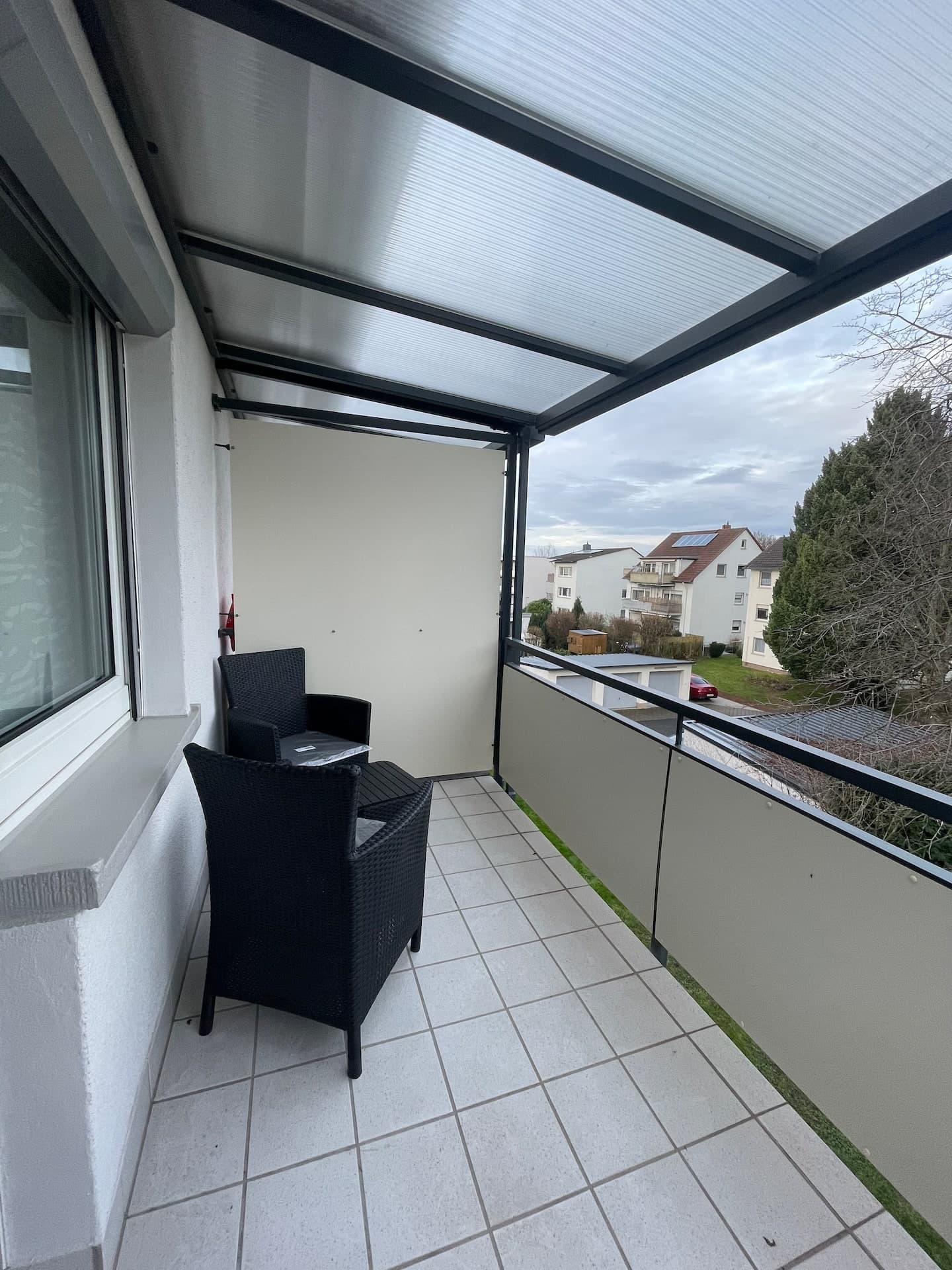 Überdachter Balkon mit Rattan-Sitzgruppe und Stadtblick